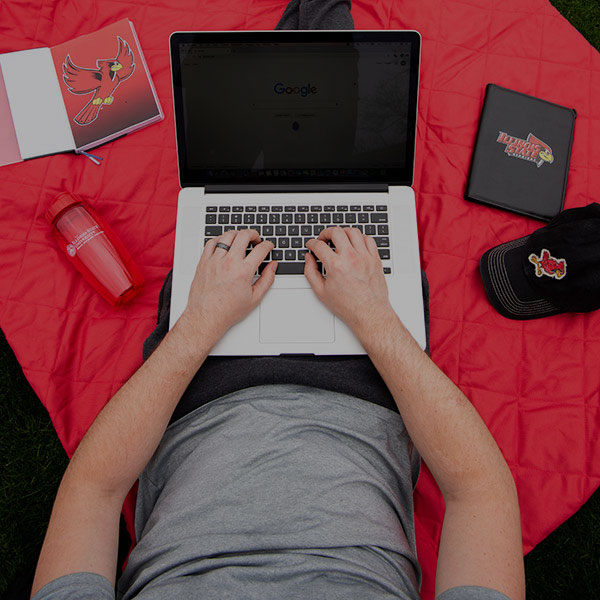 学生使用坐在红色毯子上的笔记本电脑。