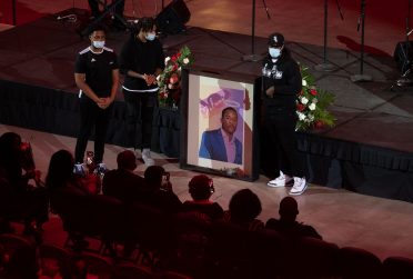 Three individuals holding a mural of Jelani Day.