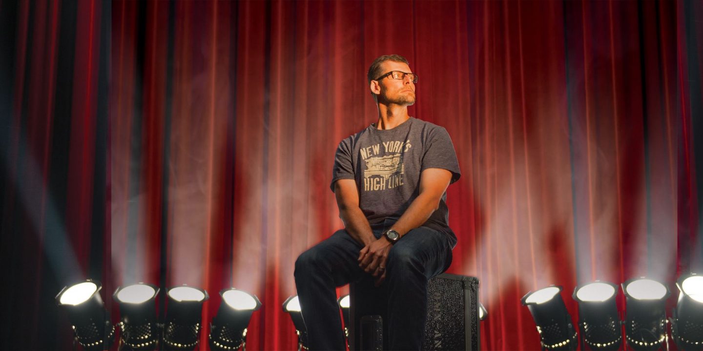 Illinois State alumni magazine cover showing lighting designer Jon Kusner onstage backlit by a row of lights